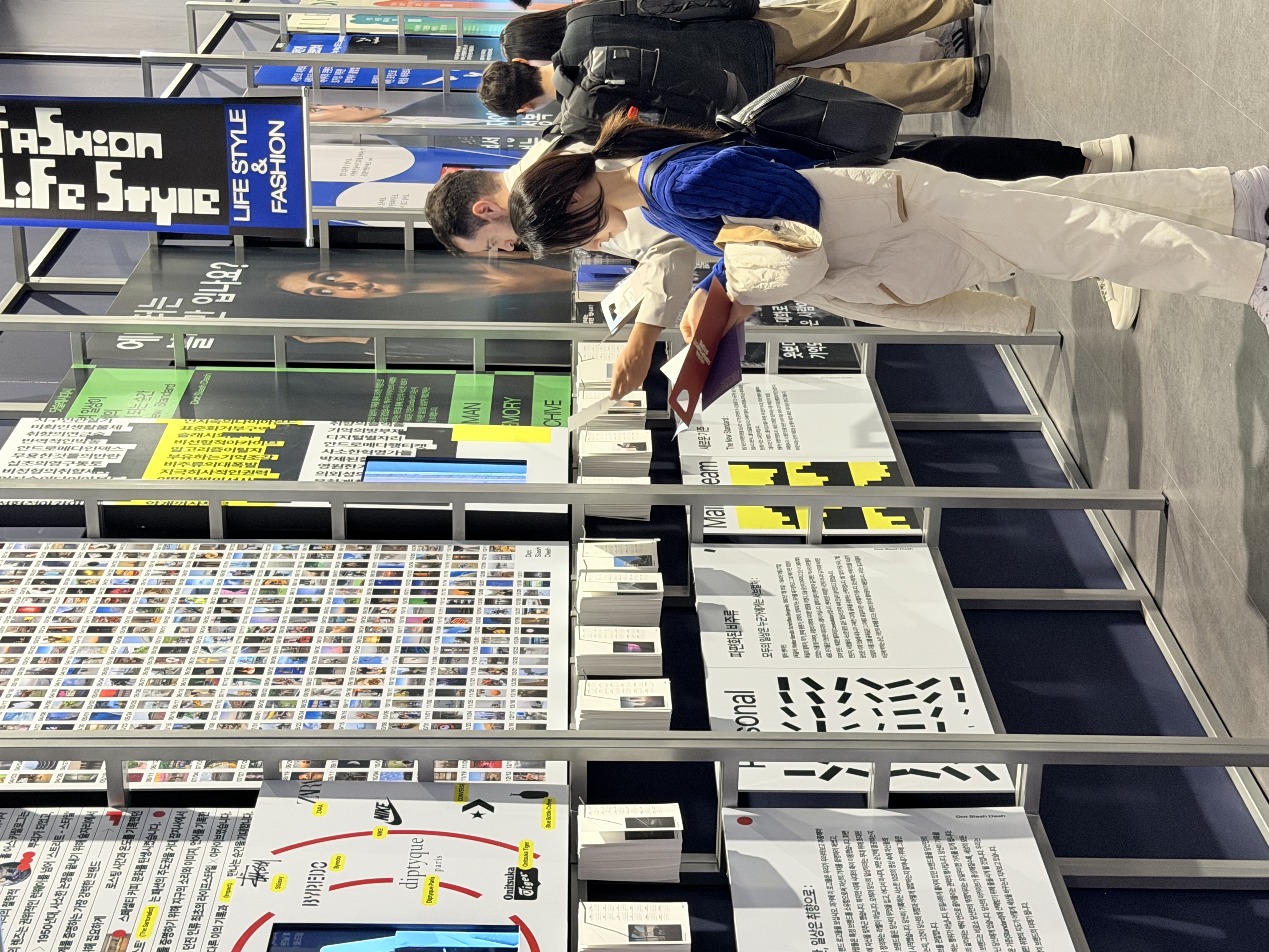 Another view of visitors examining printed pieces along the exhibition wall.